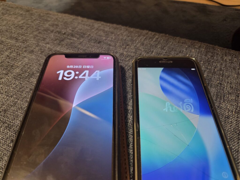 ソファの上に並べて置かれた2台のiPhone。左は19時44分を表示したロック画面、右は初期化直後の「Hello」画面が表示されている。
