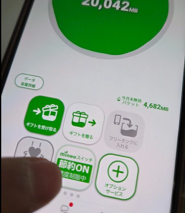 mineoアプリの「節約スイッチON」設定画面 mineoの公式アプリ画面にて、データ残量が「20,042MB」と表示され、その下に「今月末無効パケット 4,682MB」と記載されている様子。画面下部では「mineoスイッチ 節約ON 速度制限中」のボタンが緑色に点灯しており、ユーザーが任意で通信速度を制限しパケットを消費しない設定にしている状態を示している。
