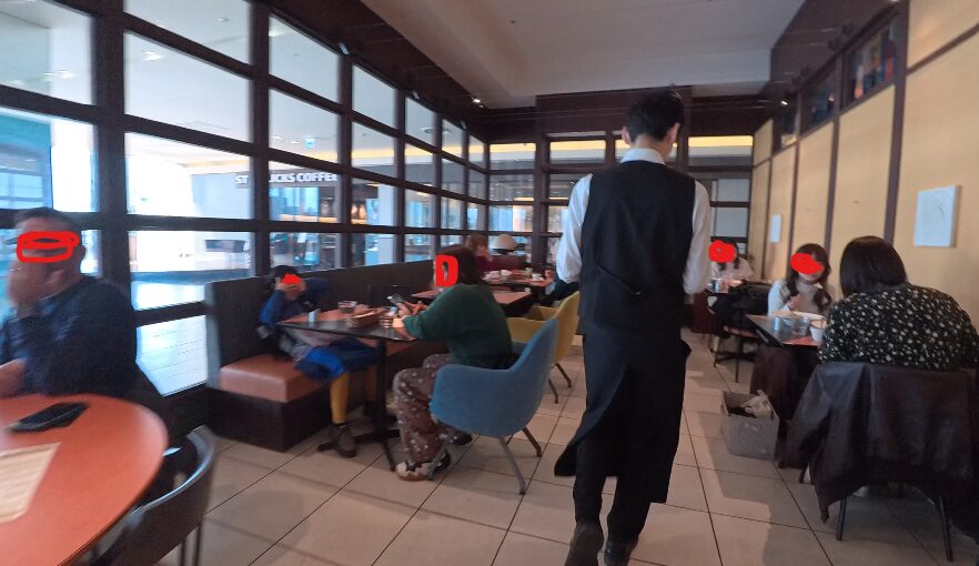 金沢フォーラス内のレストランにおける、お昼時の店内の混雑状況を映した現地写真。多くのテーブルが埋まっており、背を向けて歩くスタッフや食事を楽しむ複数のグループが写っている。

窓の外には隣接するスターバックスコーヒーの看板も見え、商業施設内の活気ある雰囲気とともに、多くの利用者が同時にスマートフォンなどの通信端末を使用していることが推測される環境である。この混雑した実環境下において、前述の通信速度測定が行われたことを裏付ける、現場の臨場感を伝える一次情報画像となっている。